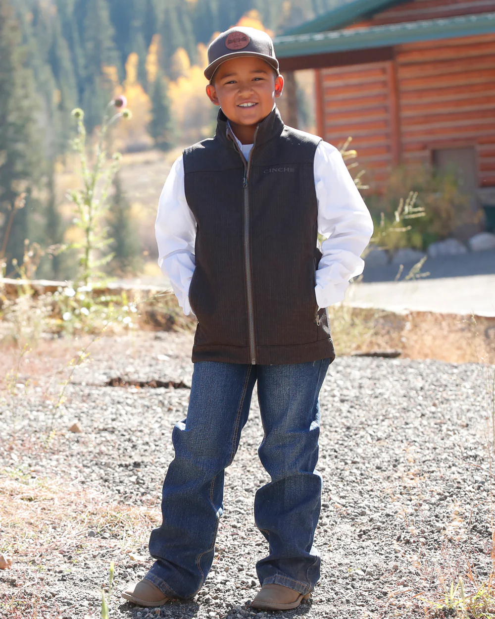 Full body view of boy wearing brown Cinch bonded vest with jeans