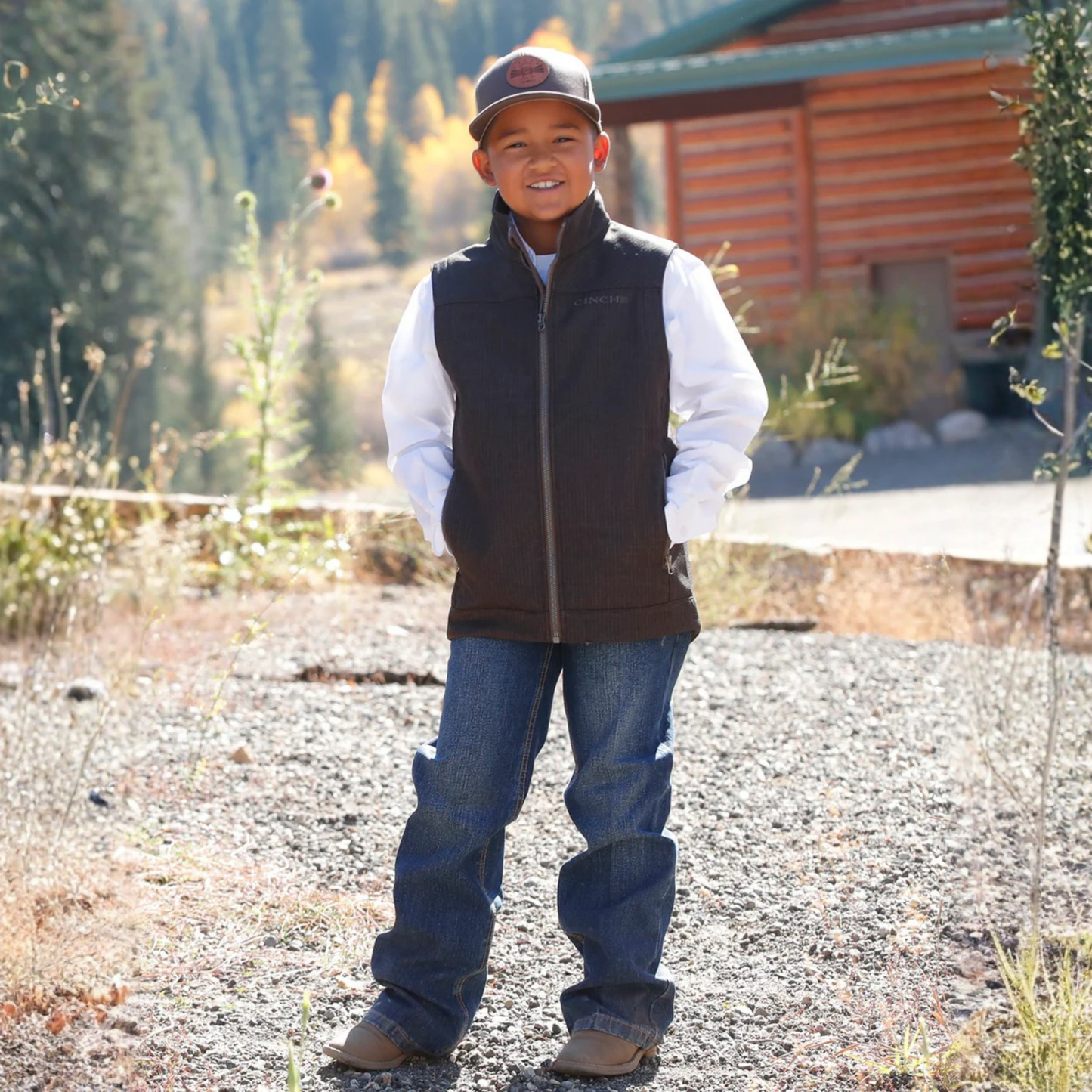 Full body view of boy wearing brown Cinch bonded vest with jeans